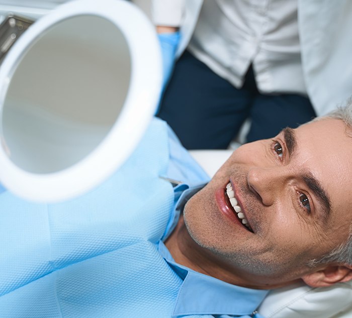 Smiling dental patient looking in mirror