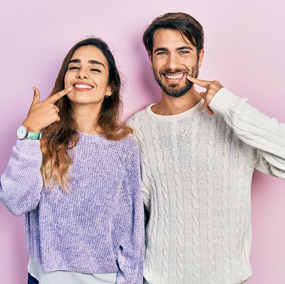 Happy couple pointing at their teeth