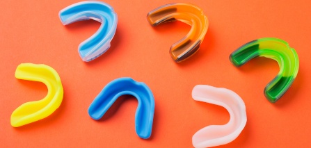 An assortment of colorful mouthguards on an orange background