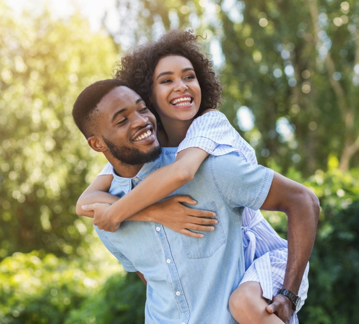 Smiling man giving woman piggyback ride outdoors